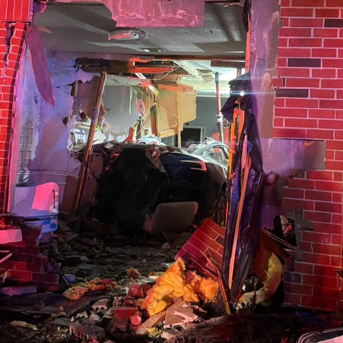 Damaged Tesla inside a home, with debris and structural damage visible.